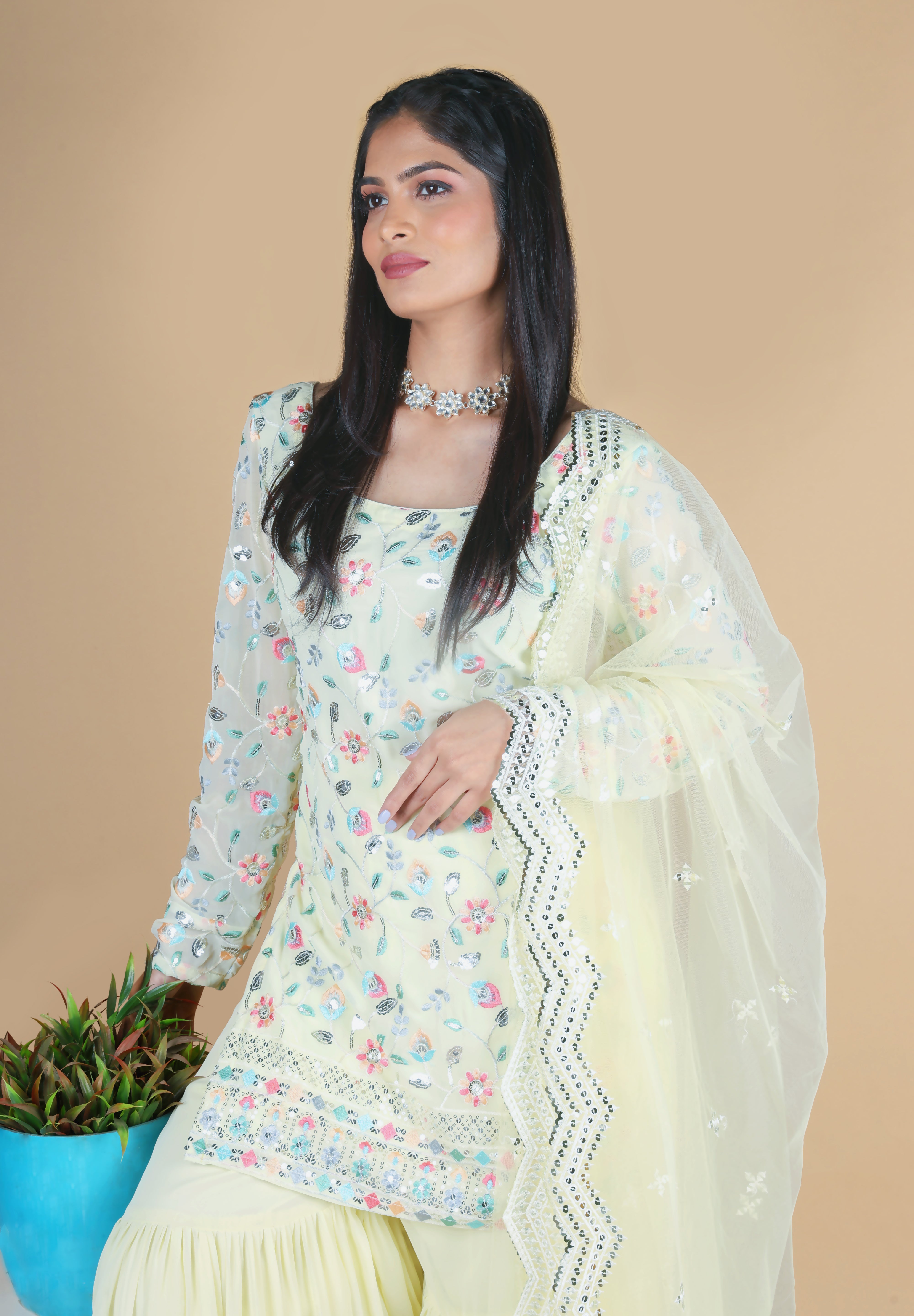 Light yellow sharara suit with embroidery work. It has a plain sharara and net dupatta. 